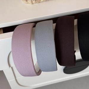 Détail de quatre serre-têtes larges à rayures en rose, bleu, marron et noir élégant