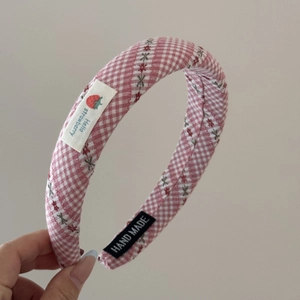 Détail du serre-tête à carreaux avec écusson fraise et étiquette fait main