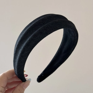 Detailed close-up of a thick black textured fabric headband with pleated 3D structure