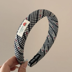 Gros plan détaillé sur un serre-tête vichy fait main avec broderie fraise et étiquette