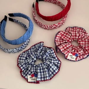 Detail von blau-rot karierten Haargummis und Stirnbändern mit bunten Knöpfen