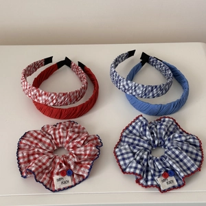 Detail von rot-blau karierten Scrunchies und Stirnbändern mit dekorativen Knöpfen