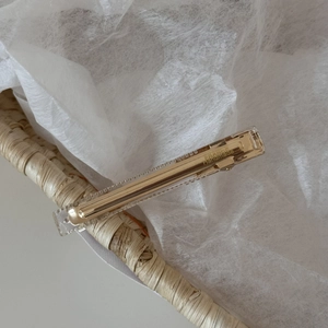 Detail of a transparent acrylic hair clip with a gold metal base and handmade engraving