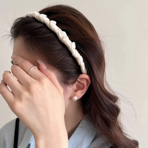 Detailed texture of ivory satin twisted headband worn by model showing elegant glossy finish
