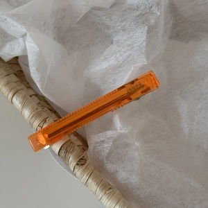 Detail of orange acetate hair clip with gold France Handmade lettering on woven basket