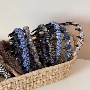 Detail view of plaid ruffled headbands with teeth combs inside a woven basket