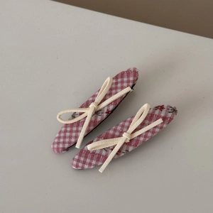 Détail de barrettes à carreaux rouges avec motifs floraux et nœuds blanc crème