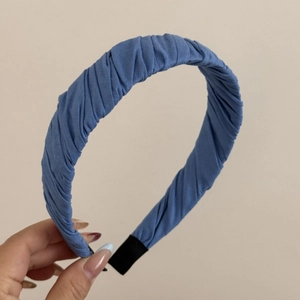 Detail eines blauen Haarreifens mit plissiertem Stoff und gleichmäßiger horizontaler Textur