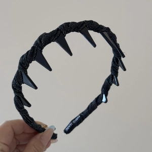 Détail d'un serre-tête tressé noir avec pointes punk et étiquette de fabrication à la main