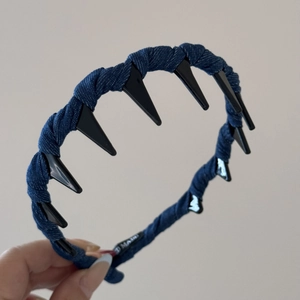 Détail d'un serre-tête en denim bleu foncé avec des pointes noires et une étiquette