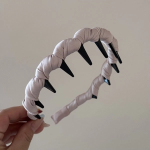Detail of wavy beige satin headband showing internal black comb teeth for hair grip
