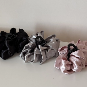 Close-up of three pleated satin hair claws in black, silver grey and dusty pink colors