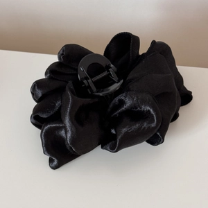 Detail of large black bubble fabric claw clip with elegant pleated satin texture