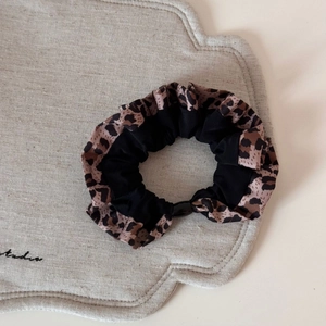 Gros plan du chouchou en tissu léopard et noir sur un tapis en lin décoratif