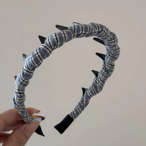 Detail of blue plaid fabric headband with black wavy teeth for secure hair styling