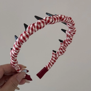 Detail showing the red gingham fabric texture and black cone spikes on the headband