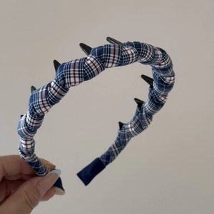 Detail of red and blue plaid headband featuring wavy inner teeth for secure hair grip