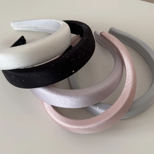 Macro detail of glossy satin headbands with fine glitter texture in multiple colors