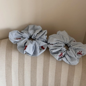 Détails de chouchous à rayures bleues avec broderies de cerises et nœuds rouges