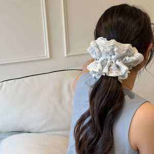 Dettaglio di elastico per capelli in pizzo azzurro con ricami e trama a balze