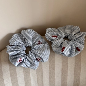 Détail de chouchous à rayures bleues avec broderies de cerises et nœuds rouges