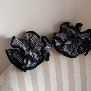 Detail of two black and white checkered scrunchies with black piping on striped fabric