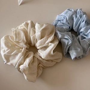 Dettaglio di elastici scrunchie in pizzo crema e azzurro con ricami floreali e righe