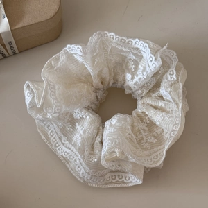 Dettaglio ravvicinato di elastico in pizzo crema con ricami raffinati e trama a pieghe