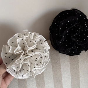 Detail of elegant polka dot pleated fabric hair claw clips in black and white colors