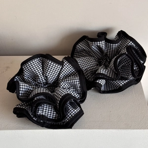 Close-up of two black and white checkered oversized scrunchies with elegant ruffled edges