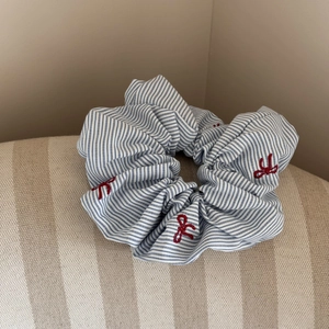 Détail du chouchou à rayures bleues avec nœuds rouges brodés et texture de tissu