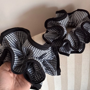 Detail of two black and white gingham scrunchies with elegant ruffled edges and elastic band