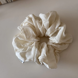 Dettaglio dell'elastico scrunchie crema a righe con ricami floreali ed etichetta