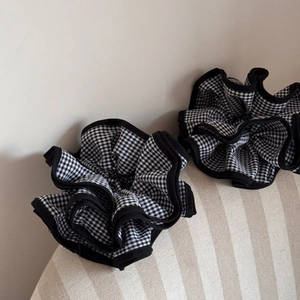 Detailed close-up of two large black and white gingham scrunchies with elegant ruffled edges