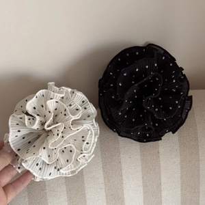 Detail of elegant black and white polka dot chiffon hair claws on beige fabric