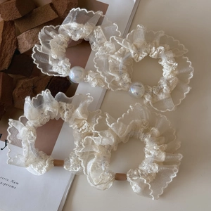 Close-up of cream lace organza hair scrunchies with elegant faux pearl embellishments