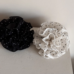 Close-up detail of black and white polka dot chiffon fabric ruffles on hair claw clips