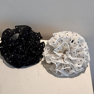 Detailed macro view of polka dot pleated fabric hair claw clips in black and white