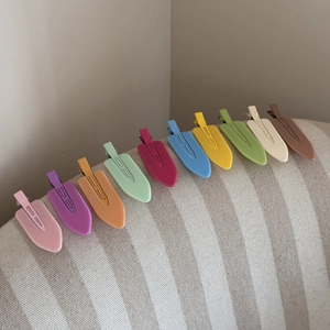 Set of ten colorful matte hair clips in candy colors arranged on beige fabric background