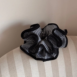 Detail of a large black and white checkered scrunchie with ruffled edges on fabric