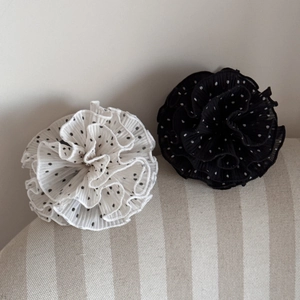 Detail of elegant polka dot fabric hair claws with pleated flower design in black and white