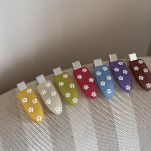 Vue détaillée de sept barrettes à fleurs en acrylique coloré avec finition mate