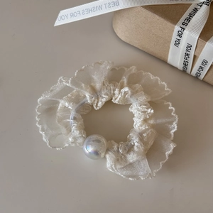 Close-up of creamy white organza scrunchie with lace embroidery and iridescent pearl
