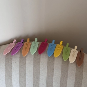 Set of 11 colorful metal duckbill hair clips neatly arranged on a fabric edge