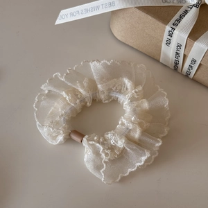 Detail of elegant white lace organza scrunchie with delicate embroidery and wavy edges