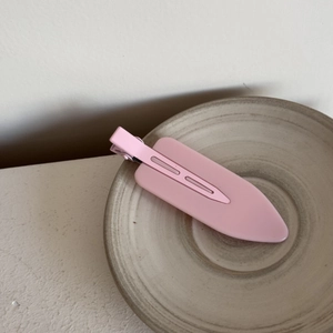 Detail shot of a matte pink traceless hair clip on a minimalist ceramic tray
