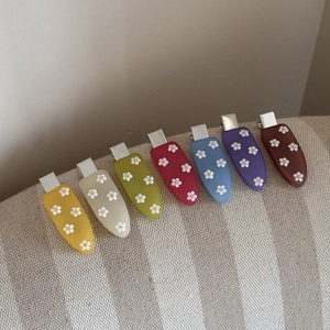 Gros plan de 7 barrettes fleurs en acrylique coloré avec finition en résine mate