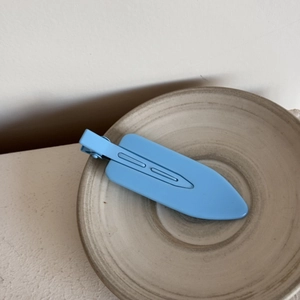 Close-up of a matte light blue seamless hair clip on a minimalist ceramic plate