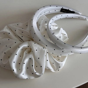 Close-up of white satin headband and scrunchie set with classic black polka dot pattern