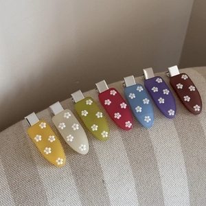 Détail de pinces à cheveux en acrylique colorées avec motifs fleurs sur tissu